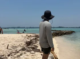 Persona de espaldas frente al mar, en una playa de arena clara